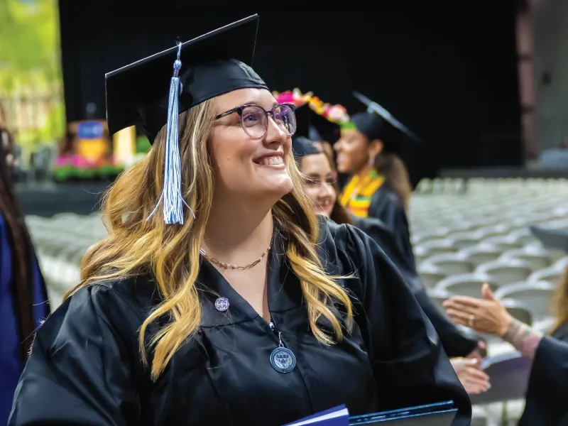 Bachelor student smiling during commencement ceremony.